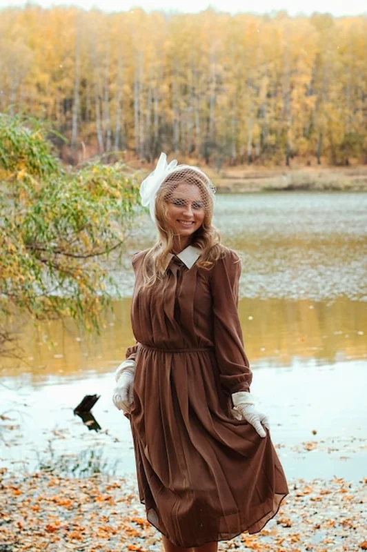 Młoda kobieta w sukience retro i uśmiechając się w jesiennym parku