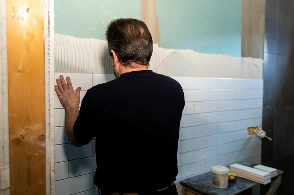Profesjonalny płytkarz układający płytki ceramiczne na ścianie łazienki