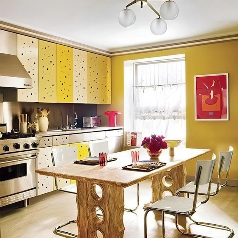 Kuchnia z żółtymi szafkami i czerwonym obrazem na ścianie