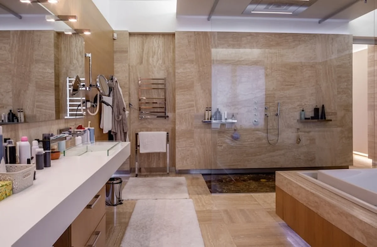 Przestronna łazienka z marmurowymi ścianami, kabiną prysznicową, lustrem i nowoczesną armaturą