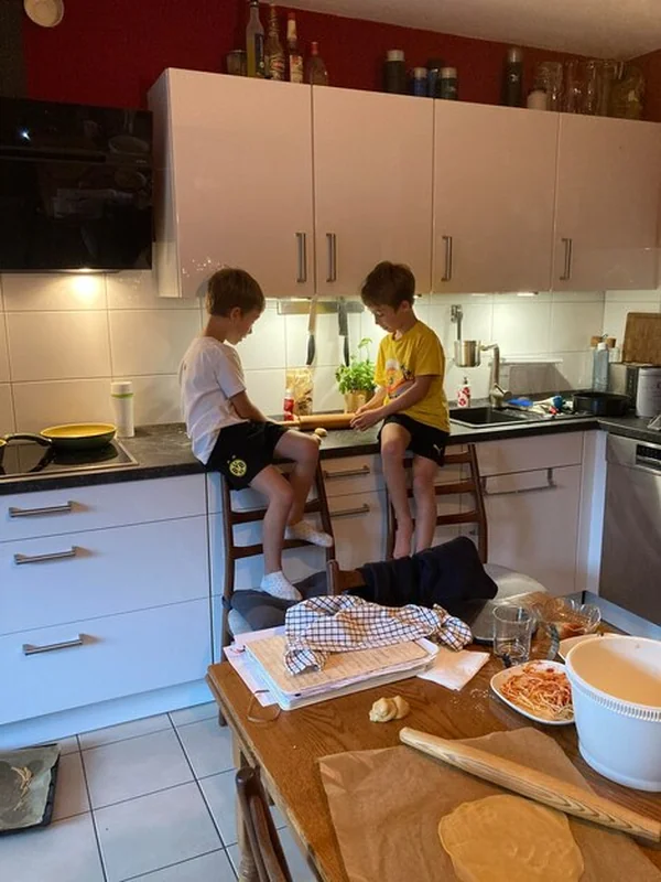 Dwa chłopcy siedzący na stole w białej kuchni