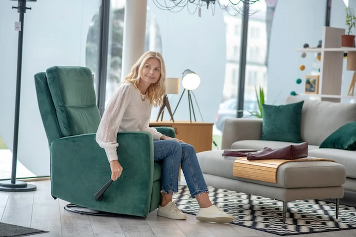 Blondynka siedząca w wygodnym fotelu w salonie meblowym, trzymająca dźwignię ręką