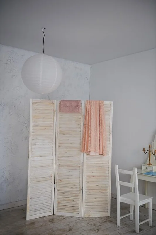 Duży pokój z drewnianym parawanem i dwiema koronkowymi sukienkami